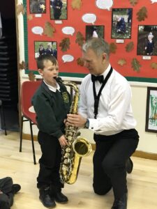 child exploring the saxophone with the help of a professional musician